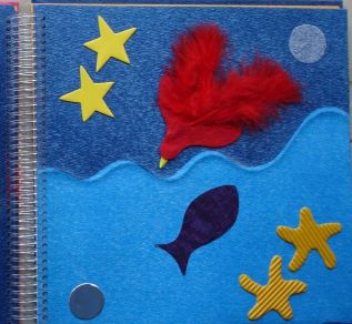 A page from a collage tactile book showing fish and two starfish in the sea, and a star and red feathery bird in the sky